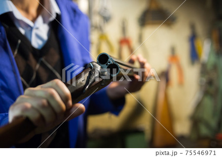 Break-action of horizontal double-barreled shotgun in hands of gunsmith 75546971