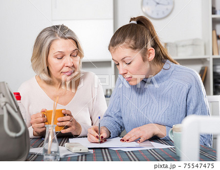 Woman and adult daughter fill out paperwork 75547475