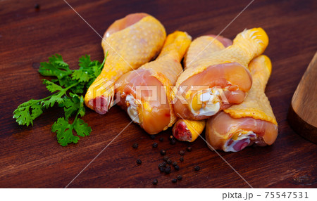 Raw chicken legs on cutting board and plate closeup Raw chicken legs on cutting board and plate closeup 75547531