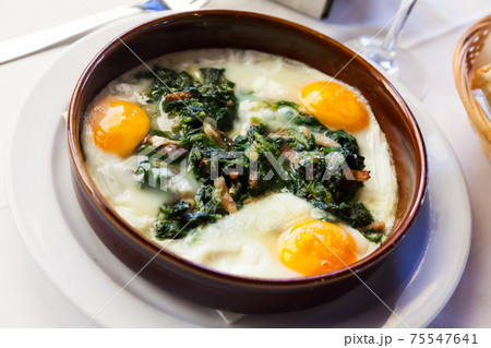 Plate with fried eggs, ham with spinach and raisins at plate 75547641