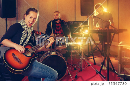 Young woman guitar player and singer with band Young woman guitar player and singer with band 75547780