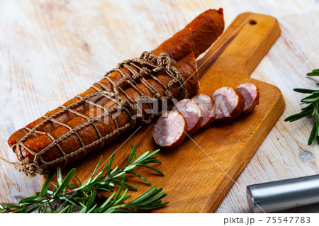 Sliced half-smoked sausages on wooden table 75547783