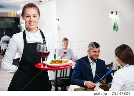 Portrait of woman waiter who is standing with dish in restaurante Portrait of woman waiter who is standing with dish in restaurante 75547832