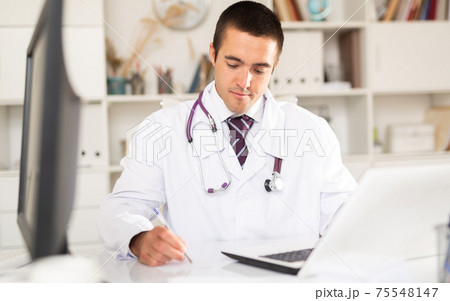 General practitioner working with case histories on laptop General practitioner working with case histories on laptop 75548147