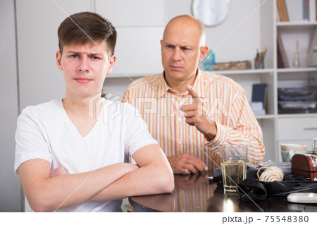 Teenager listening to reprimanding father 75548380