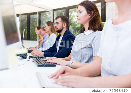 Side view of row of positive people working Side view of row of positive people working 75548410