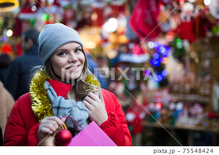 Girl choosing Christmas gifts outdoor on street market 75548424
