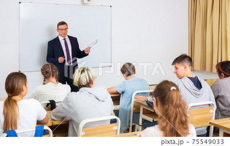 Teacher explaining studying material to teenagers during lesson Teacher explaining studying material to teenagers during lesson 75549033
