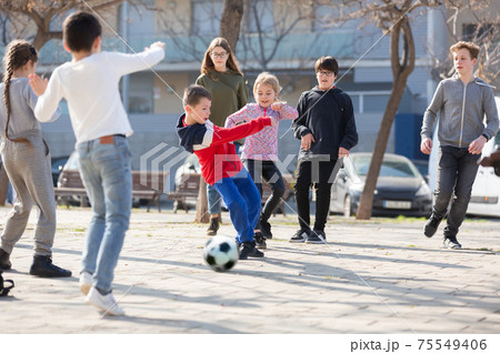 Company of glad children playing football on the street 75549406