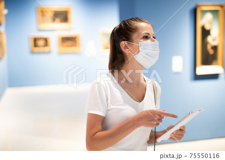 Woman in mask observing artworks in museum Woman in mask observing artworks in museum 75550116