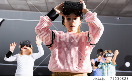 Tween girl using vr headset goggles to play exciting game 75550323