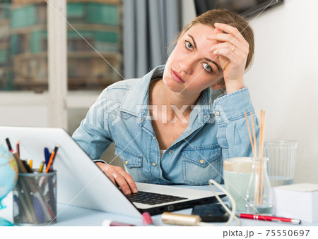 Upset young woman counts family budget on laptop Upset young woman counts family budget on laptop 75550697