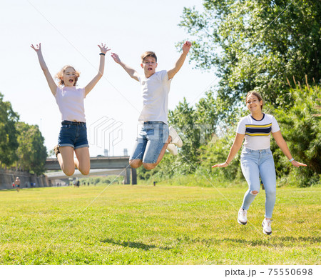 Happy teenagers jumping on the green lawn 75550698
