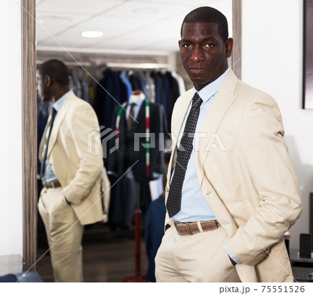 Confident male customer choosing fashion beige suit in mens store 75551526