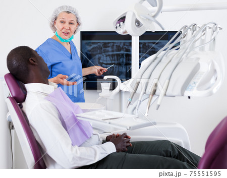 Doctor woman dentist shows patient an x-ray 75551595