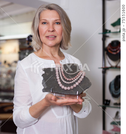 Woman offering to buy fashionable rose quartz necklace in the shop of jewelry 75551600