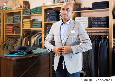 Man choosing suit jacket in clothing store 75552024