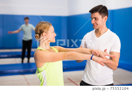 Trampoline trainer teaching female gymnast 75552104