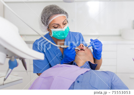 adult dentist checking teeth of patient 75553053