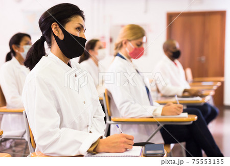 Asian woman in protective mask making notes at medical seminar 75553135