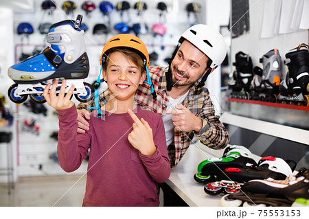 Father and son showing roller-skates they bought in sports store 75553153
