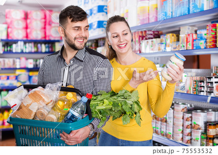 Portrait of couple with shopping basket filled food products Portrait of couple with shopping basket filled food products 75553532