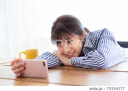 スマホで動画視聴を楽しむ若い女性 75554277