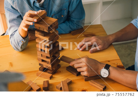 Group of Friends playing blocks wood game on the table folded puzzle holding blocks wood game. Group of Friends playing blocks wood game on the table folded puzzle holding blocks wood game. 75557762