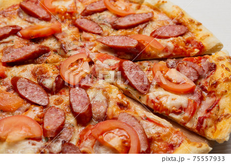 Italian pizza with smoked sausage slices and tomatoes, pizza cut, close-up 75557933