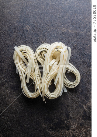 Dried white rice noodles. Raw pasta. Uncooked noodles. 75558019