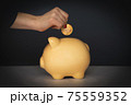 Crop woman putting coin in piggy bank 75559352
