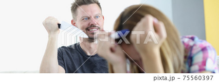 Proofing woman holding pregnancy test with her head bowed beside an angry man with knife. Proofing woman holding pregnancy test with her head bowed beside an angry man with knife. 75560397