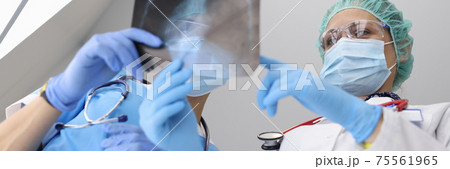 Two doctors in protective mask discuss x-ray of lungs with atypical pneumonia in hospital in covid epidemic. 75561965