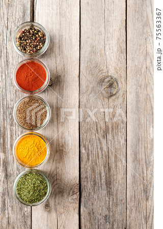 Colourful spices in bowls on wooden table with copyspace. Big collection of spices. Top view 75563367