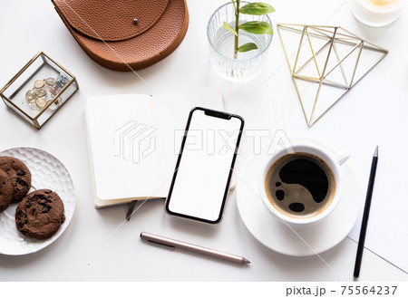 White home office tabletop with smartphone mock-up, coffee cup and notepad White home office tabletop with smartphone mock-up, coffee cup and notepad 75564237