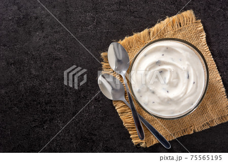 Stracciatella yogurt with chocolate chips in transparent bowl on black background 75565195