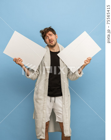 Caucasian man in white bathrobe with sheets of paper isolated on blue background 75565415