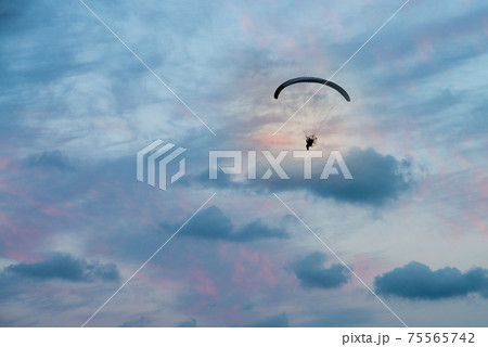 paramotor flight in horizontal sunset sky 75565742
