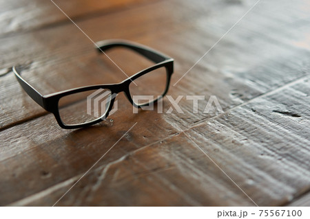 ウッドテーブルに置かれた眼鏡 75567100