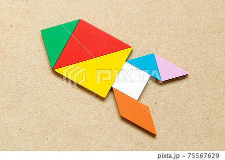 Color tangram puzzle in missile or rocket shape on wood background Color tangram puzzle in missile or rocket shape on wood background 75567629