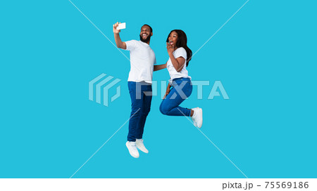 Black couple taking selfie and jumping at studio Black couple taking selfie and jumping at studio 75569186