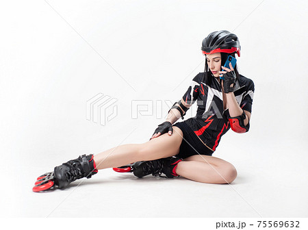 a slender woman in sportswear and a helmet on roller skates on a white background is talking on the phone a slender woman in sportswear and a helmet on roller skates on a white background is talking on the phone 75569632