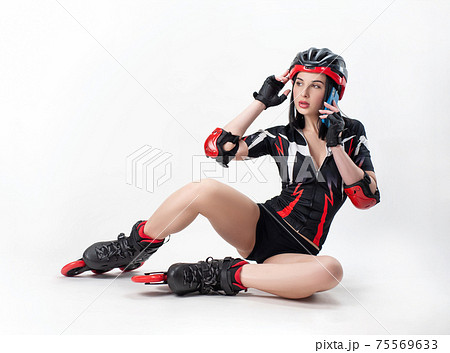 a slender woman in sportswear and a helmet on roller skates on a white background is talking on the phone 75569633