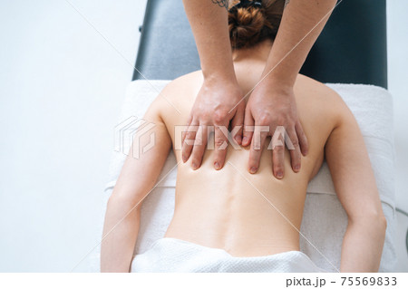 Top close-up view of male masseur massaging back and shoulders of female lying on massage table 75569833