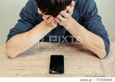 frustrated young man looking at his broken smartphone. frustrated young man looking at his broken smartphone. 75569868