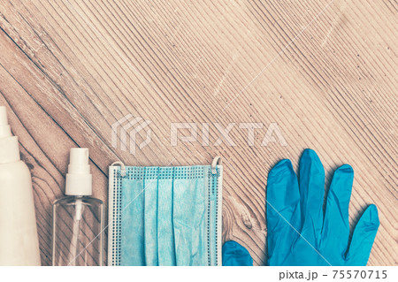 disinfecting liquid, spray, protective mask and gloves on a wooden table 75570715