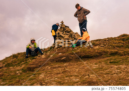 A group of tourists sits on top of the mountain in sportswear, the Montenegrin ridge and the top of Mount Rebra. 75574805