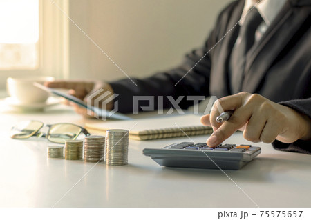 The businessman is holding a pen and pressing to a calculator, ideas for planning for investment and money growth. 75575657