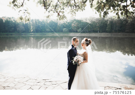 Perfect couple bride, groom posing and kissing in their wedding day Perfect couple bride, groom posing and kissing in their wedding day 75576125