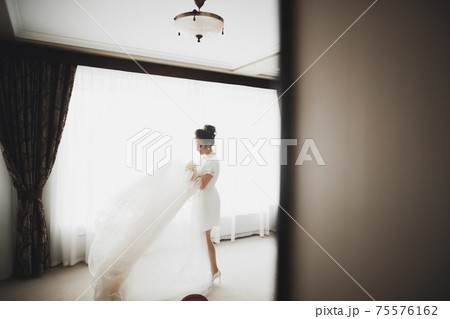 Luxury bride in white dress posing while preparing for the wedding ceremony Luxury bride in white dress posing while preparing for the wedding ceremony 75576162